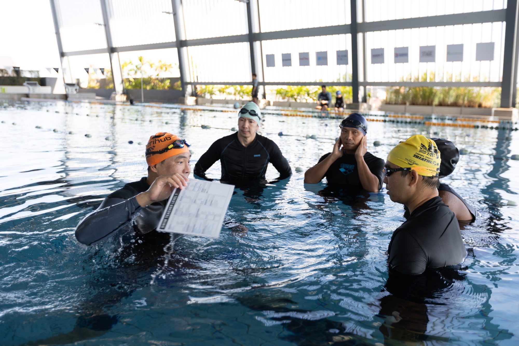 โค้ช SSI สาธิตแผนการสอนให้ผู้เข้าอบรมในสระ · SSI coach reviewing a lesson plan with trainee teachers in the pool