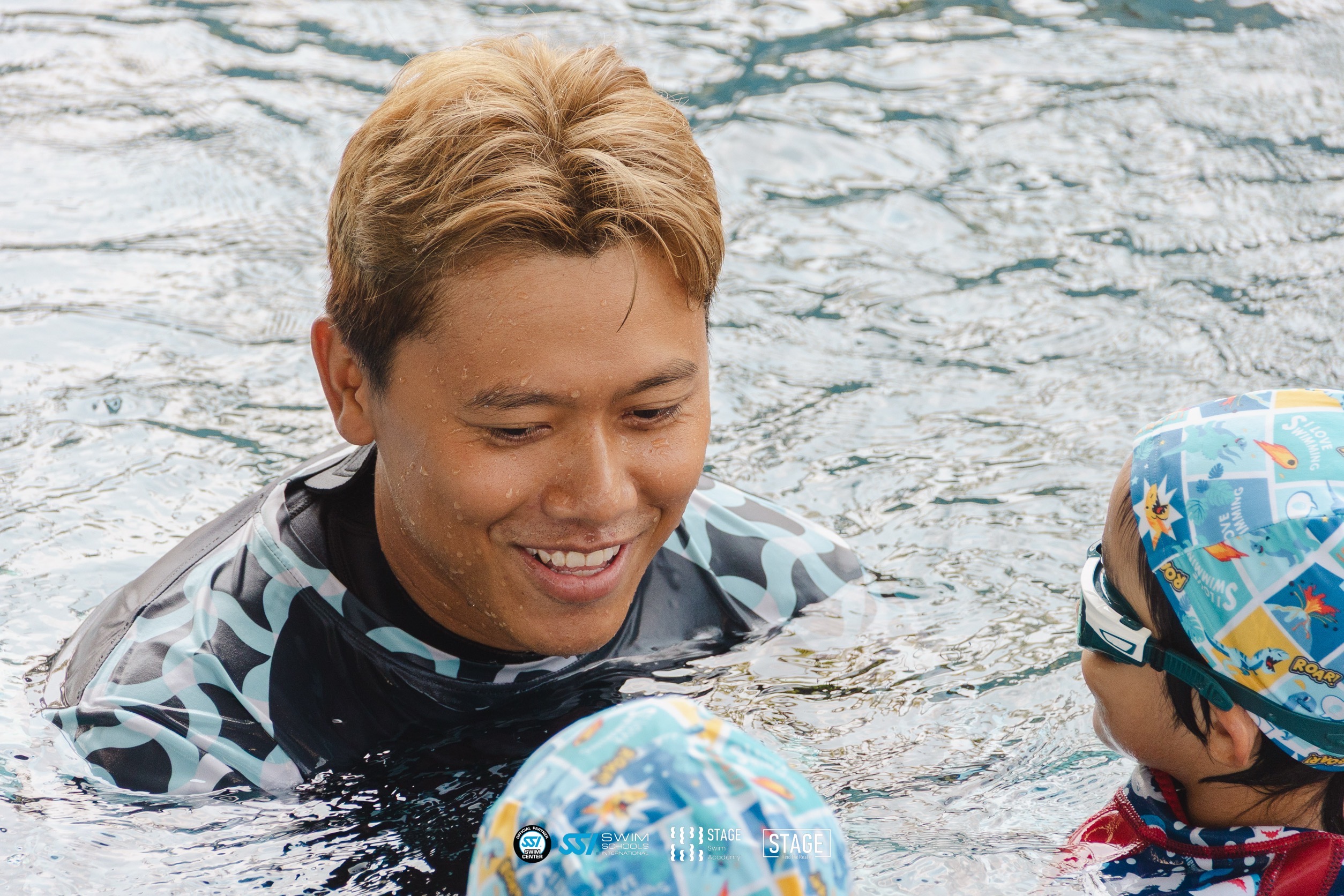 Smiling STAGE coach with kids in the pool